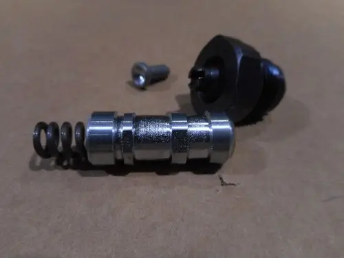 Eine Druckregelvorrichtung, bestehend aus einem Metallteil mit einer Feder und einer Schraube, von der Marke Remeha, auf einer braunen Unterlage.